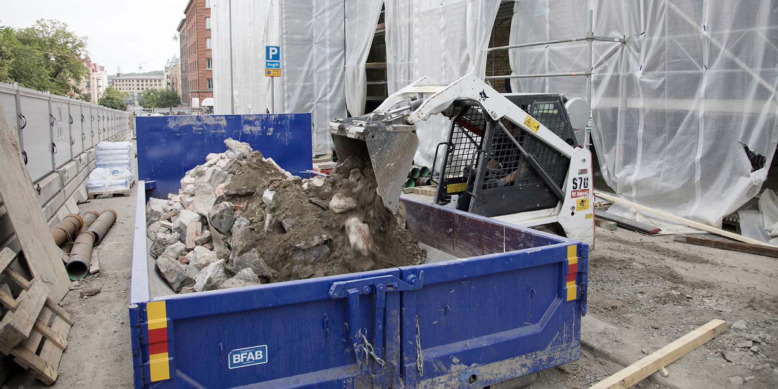 Foto av en grävskopa som hällergatsten och grus container utanför teaterhuset.